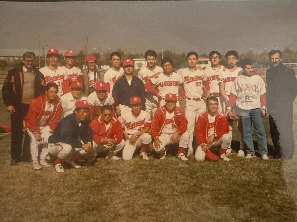 A large group posing on grass, including people wearing red-and-white sports clothing.
